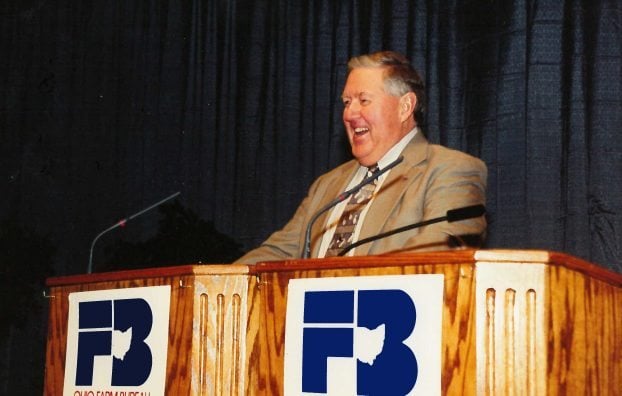 Kenny Walter smiling while giving speech in front of a lectern